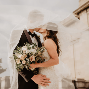 Couple kissing un der a wedding veil showing one of the wedding veil styles you can have as a bride